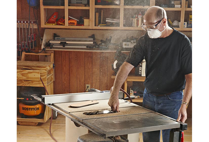 Showing someone at a tablesaw with dust flying in the air.
