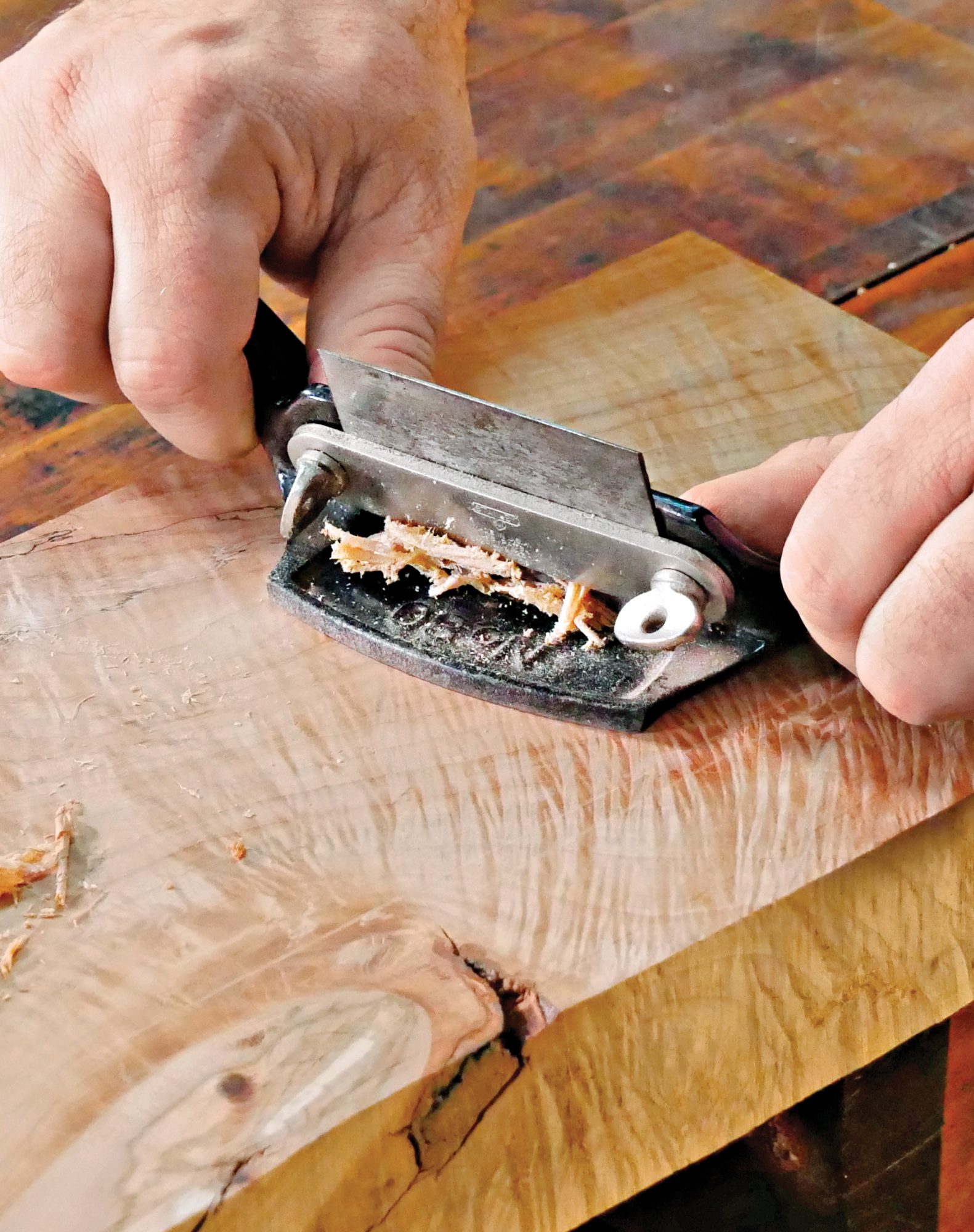 Photo of hands using hand plane on material