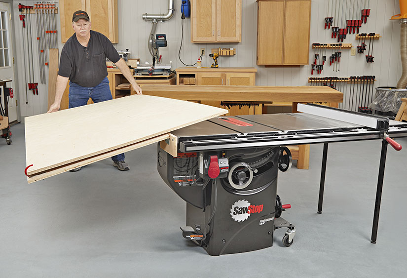Man putting large board on tablesaw.
