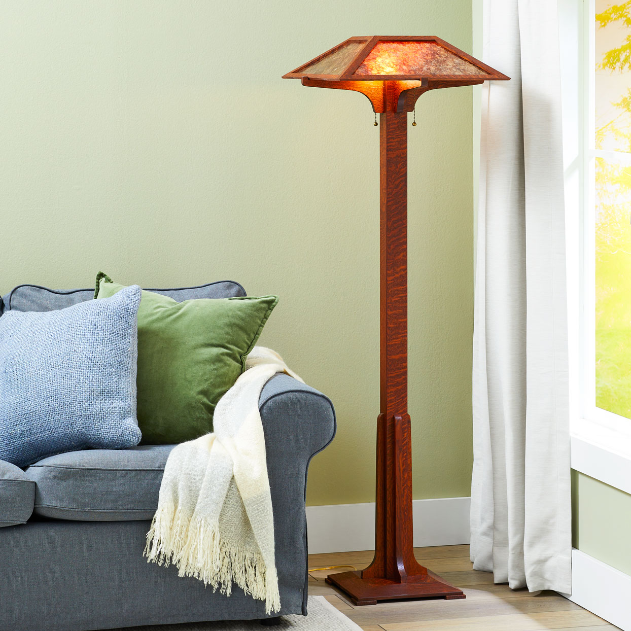 Mission style tall lamp standing between couch and windwo